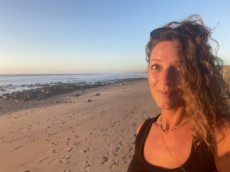 Portrait de Céline, fondatrice d’Immersive Expérience, à la plage, illustrant son parcours de passion pour l’art du bien-être et du massage.