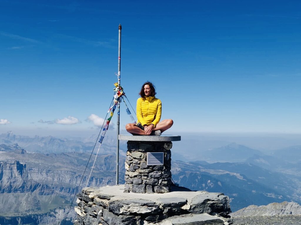 Céline, fondatrice d’Immersive Expérience, assise en méditation au sommet d’une montagne, symbolisant la connexion avec la nature et l’esprit.