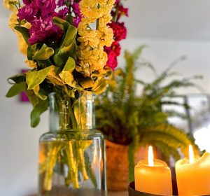 Bouquet de fleurs colorées et bougies allumées, symbolisant l’ambiance naturelle et chaleureuse des soins proposés par Céline, fondatrice d’Immersive Expérience.