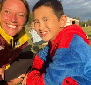 Céline avec un petit garçon mongol, partageant un sourire et un moment de connexion lors d’un voyage en Mongolie.